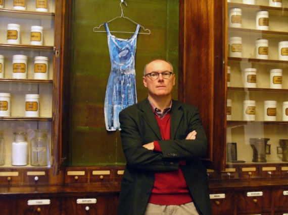 Martin Paulus vor blauem Kleid inmitten historischer Apothekenschränke