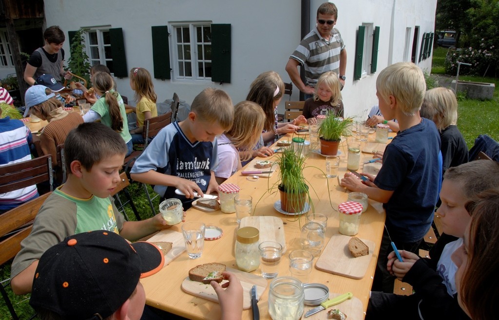 Eine Schulklasse beim Brotzeiten im Garten des Weiß-Egger-Anwesens in Ellighofen