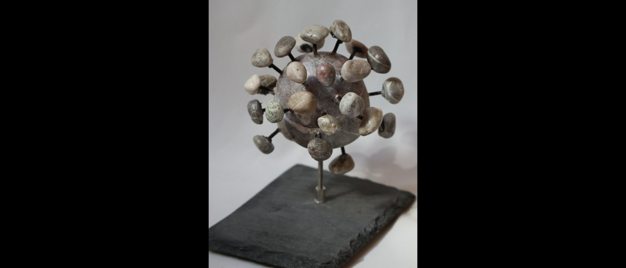 Skulptur eines Corona-Virus aus Steinen gefertigt