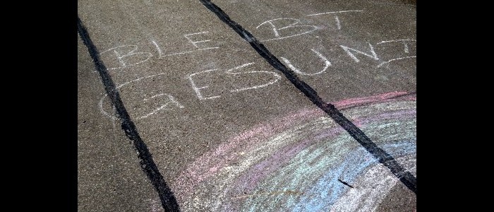 Straßenkreiden-Zeichnung eines Regenbogens und der Schrift &quot;Bleibt gesund&quot; auf Teer