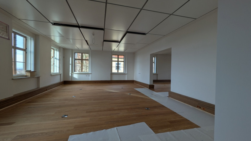 Raum mit weißen Wänden, weißen Decken und frisch verlegtem Parkettboden.