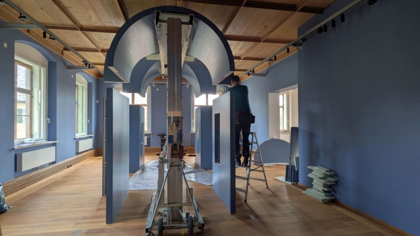 In der Mitte eines Raumes wird mit Haltevorrichtungen ein blauer Gew&ouml;lbebau aufgebaut.